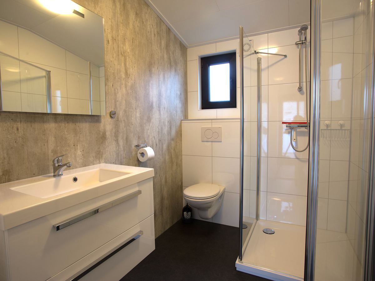 De badkamer van de boslodge met douchecabine, wastafel en toilet