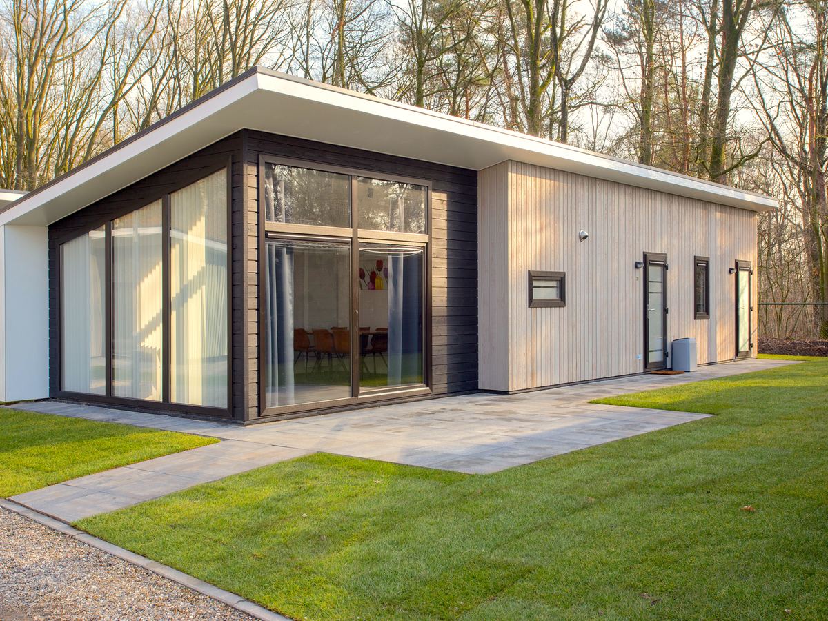 De houten boslodge met veranda tussen de bomen