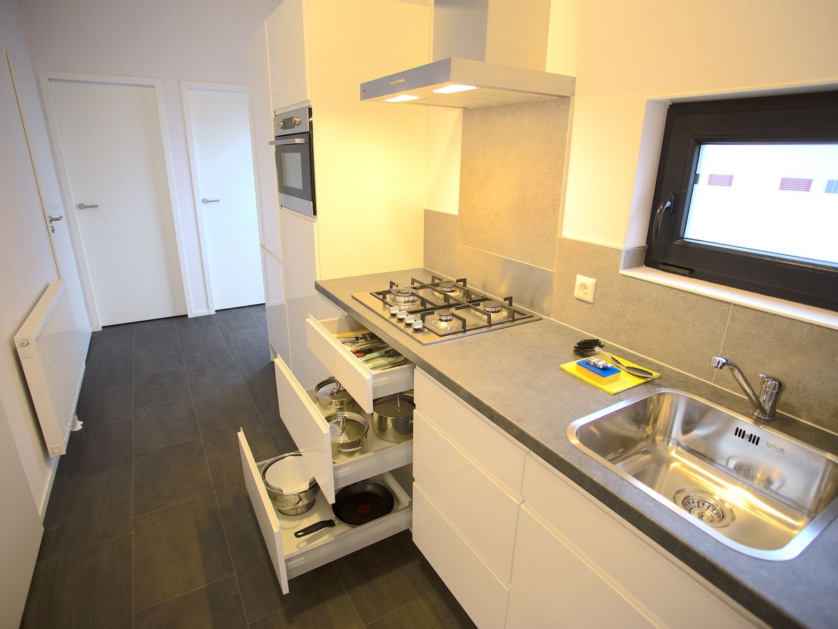 De open keuken van de boslodge met kookplaat, afzuigkap en oven