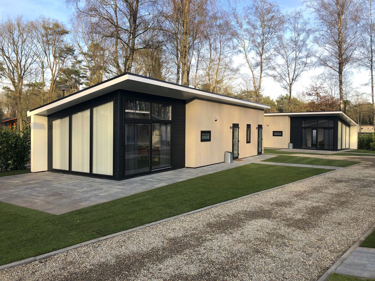 Een rij boslodges met beplanting en een pad ertussen
