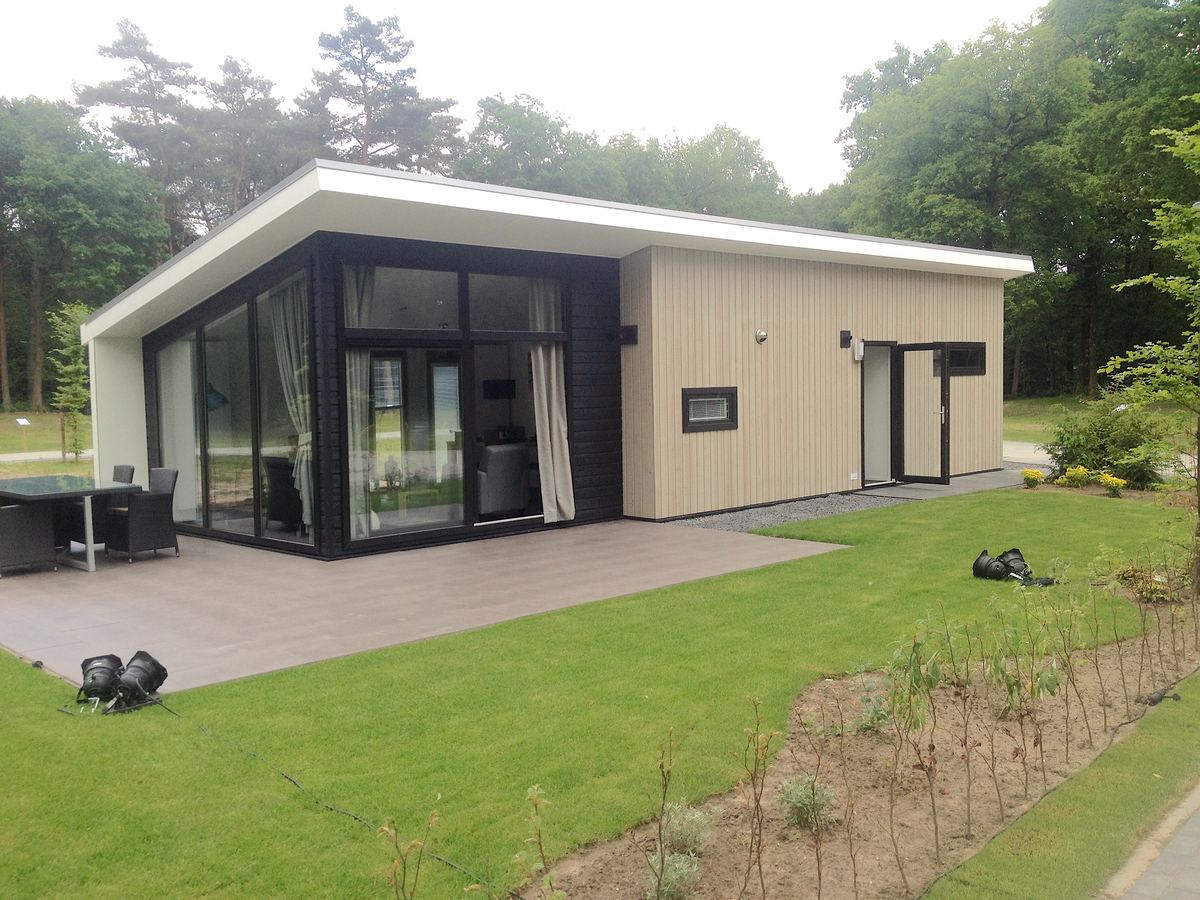 De boslodge met een grasveldje en een terras aan de zijkant