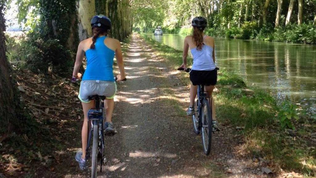 Twee fietsers op een schaduwrijk pad langs het water
