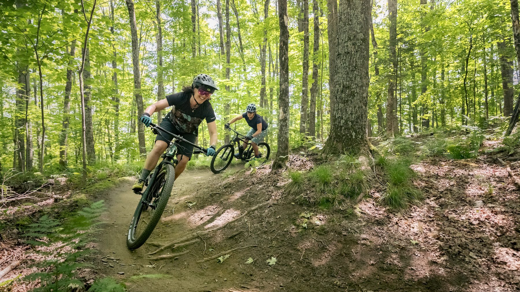 Twee mountainbikers rijden over een bospad met de wielen los van de grond