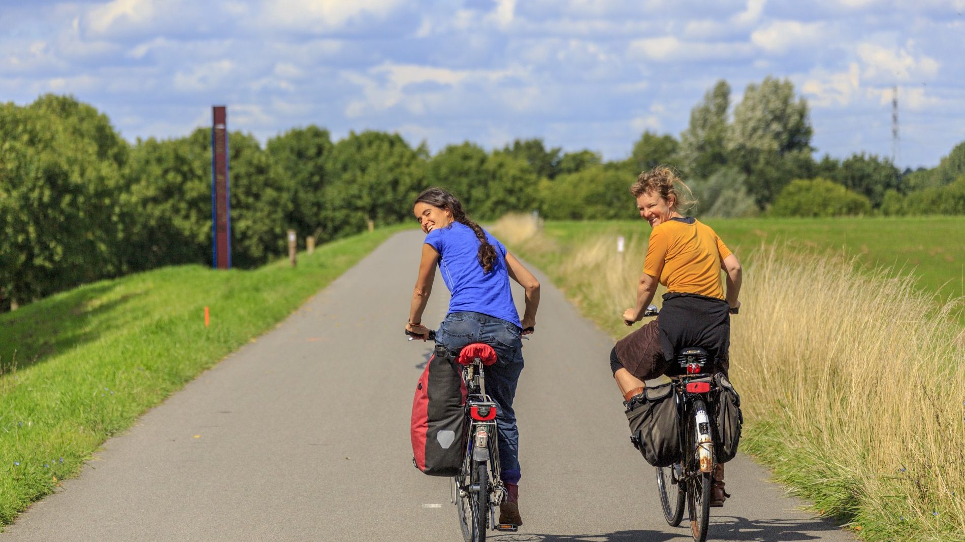 Twee fietsers met bagagetassen op een pad langs de weilanden bij Berlicum