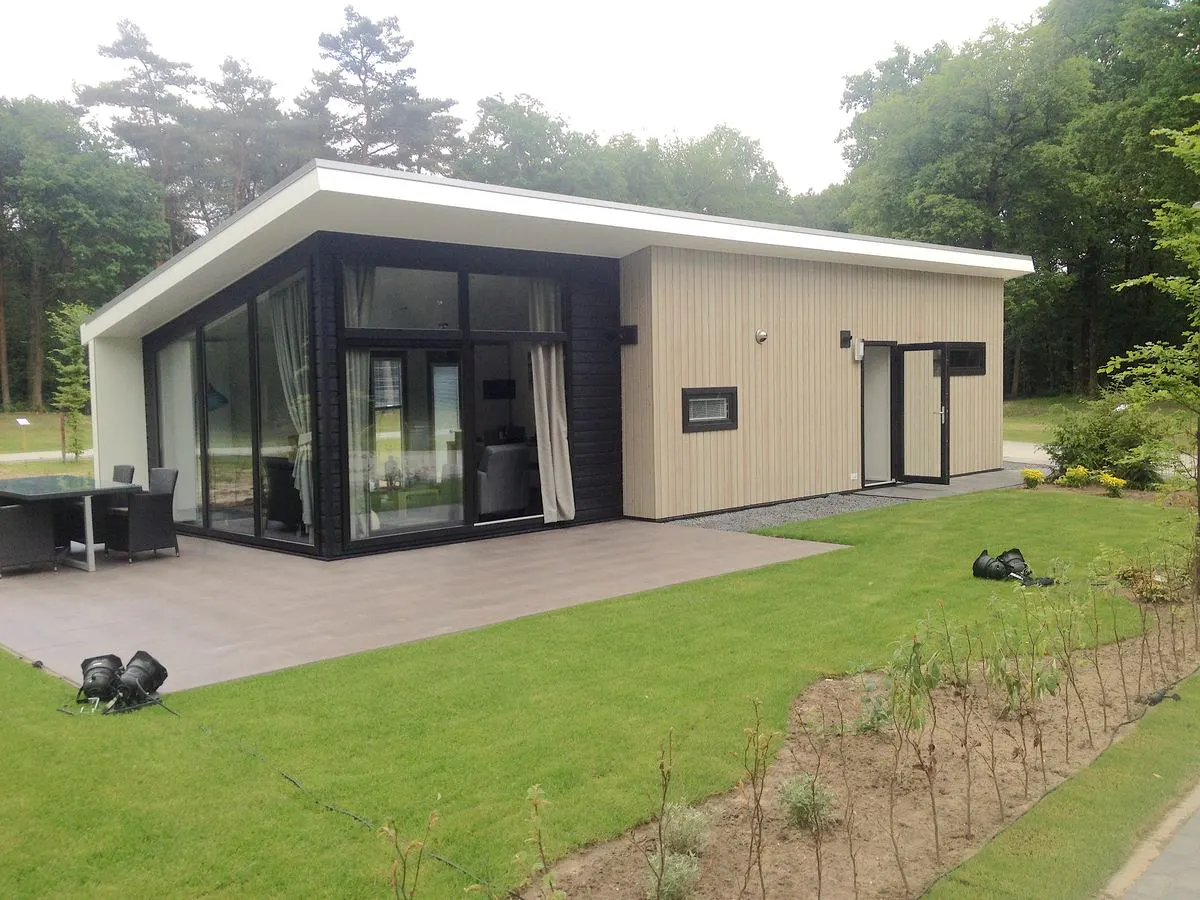 De boslodge met een grasveldje en een terras aan de zijkant