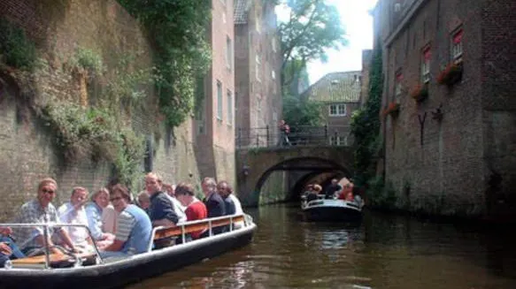 Een rondvaartboot met passagiers vaart onder een gemetselde boog door over de Binnendieze
