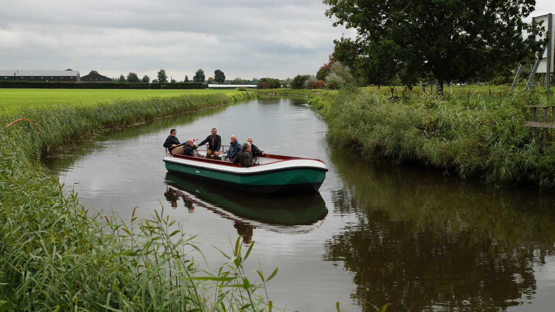 De fluisterboot met passagiers vaart door het groene beekdal van de Aa