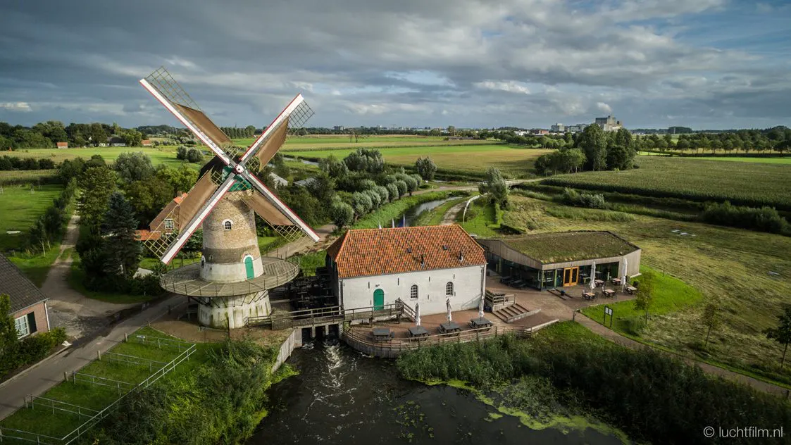 De Kilsdonkse Molen met zijn wieken boven het weiland, gezien van bovenaf