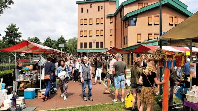 Bezoekers lopen langs de kramen op de weekmarkt bij een oud pand